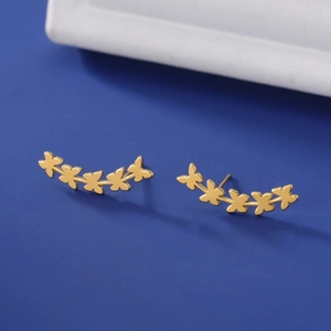 Detailed close-up of five golden butterflies stud earrings on a dark blue background