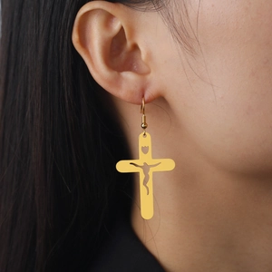 Boucles d'oreilles croix en acier titane doré avec silhouette de Jésus sur modèle
