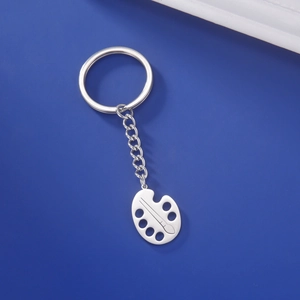 Detailed close-up of a silver stainless steel art palette and paintbrush keychain charm