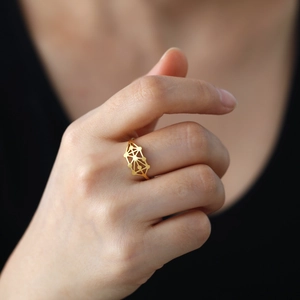 Bague géométrique ajourée en acier inoxydable doré portée sur l'index du mannequin
