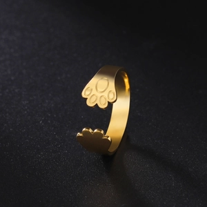 Detail of adjustable gold paw ring featuring polished feline pads on black background