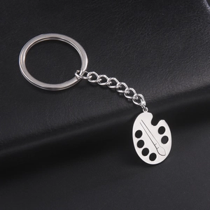 Macro view of a polished silver stainless steel keychain with palette and brush pendant