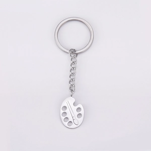 Detail shot of a silver artist palette and brush keychain made of stainless steel