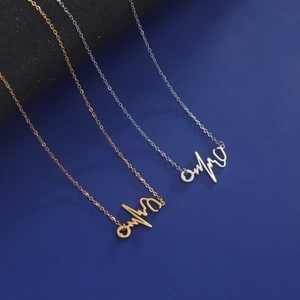 Minimalistische EKG-Herzschlag-Halskette in Gold und Silber auf dunkelblauem Hintergrund