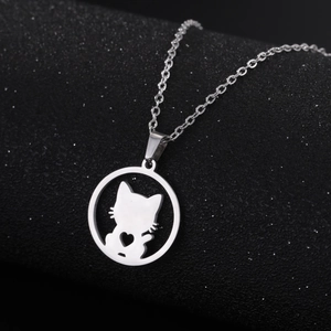 Macro shot of silver cat silhouette pendant with heart cutout on a black texture