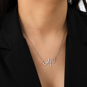 Halskette mit Herzschlag und Stethoskop auf Model mit schwarzem Blazer-Hintergrund