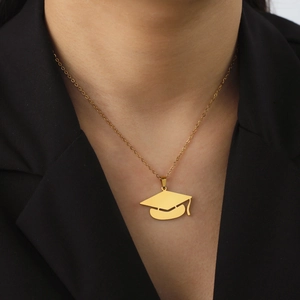 Minimalist gold graduation cap pendant necklace worn over a black blazer suit