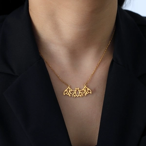 Golden hollow bat pendant necklace in stainless steel worn by a model on a black blazer