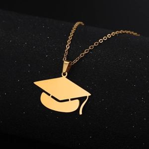 Macro view of a gold-plated stainless steel graduation cap pendant on a black surface