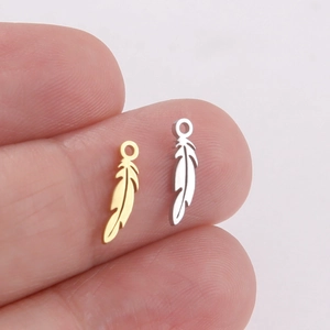 Polished stainless steel feather pendants in gold and silver finish shown on fingertips
