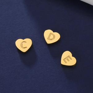 Détail macro de breloques coeur en plaqué or 18K avec lettres gravées C, D et E