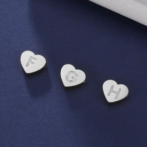 Détail macro de pendentifs cœur en acier inoxydable avec lettres gravées F, G et H