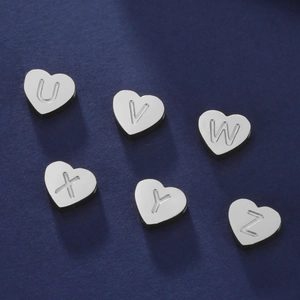 Détail de pendentifs cœur en acier inoxydable avec lettres gravées U-Z sur fond bleu