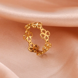 Golden titanium steel ring with hollow infinity clover pattern on orange silk fabric