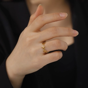 Gold stainless steel ring with continuous hollow clover design worn by a female model