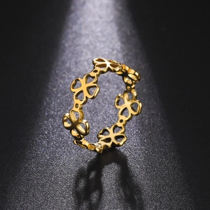 Macro view of polished golden stainless steel ring featuring hollow four-leaf clover pattern