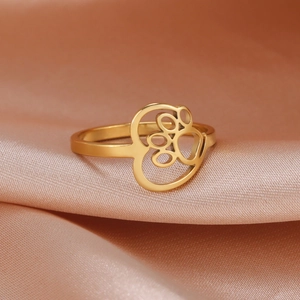 Macro view of gold stainless steel hollow cat paw heart ring on pink silk fabric
