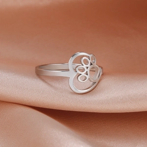 Polished stainless steel ring with cutout cat paw heart design on pink silk background