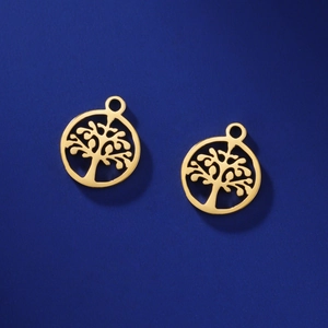 Detailed view of two gold tree of life charms with intricate hollow cutouts on blue paper