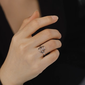 Detailed view of a silver heart-shaped ring with cat paw cutouts worn on a finger