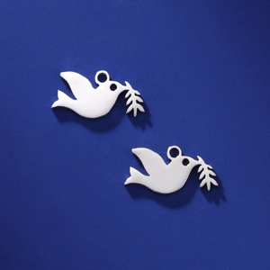 Macro view of two polished stainless steel peace dove pendants with olive branches for DIY