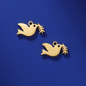 Macro shot of two gold-plated stainless steel dove charms with olive branches on blue background