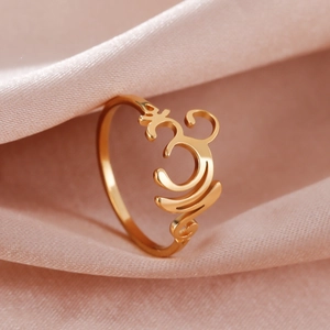 Detailansicht des polierten goldenen Om-Symbols auf elegantem rosa Seidenstoff