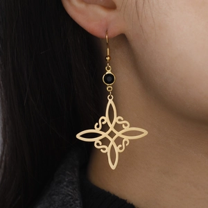Goldene keltische Knotenohrringe mit schwarzem Stein am Model für einen Retro-Stil