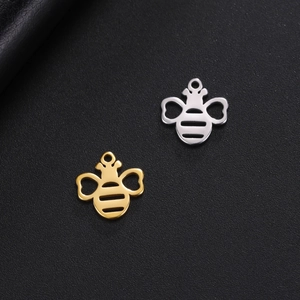 Macro detail of bee-shaped pendants in gold and silver finishes on textured leather
