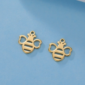Macro detail of golden honeybee pendants with heart-shaped wings and hollow body stripes