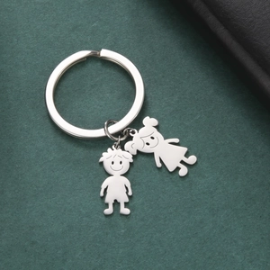 Polished stainless steel keychain with minimalist boy and girl charms on a green background