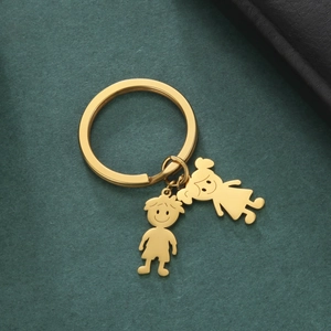 Close-up of golden cartoon boy and girl pendants on a polished stainless steel keychain