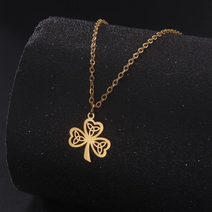 Close-up of gold clover pendant with intricate Celtic knot cutout on black display