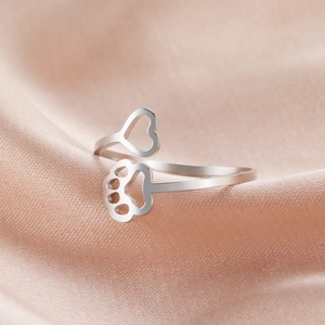 Polished open ring featuring hollow heart and dog paw prints on pink silk background