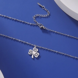 Macro detail of silver clover pendant with Celtic knot design on blue background