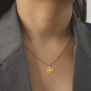Golden Celtic knot clover pendant necklace on model wearing a grey blazer jacket