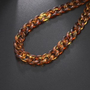 Dettaglio della catena in acrilico ambrato con maglie spesse e texture a tartaruga lucida
