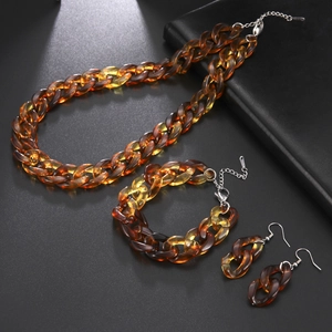 Dettaglio del set con collana a catena, bracciale e orecchini in acrilico color ambra
