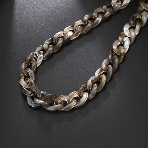 Dettaglio di una collana a catena spessa in resina con trama marmorizzata grigia e chiara