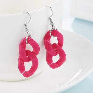 Dettaglio di orecchini a catena in acrilico rosa acceso su tazza di ceramica