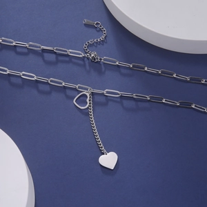 Detailed macro of silver paperclip chain necklace featuring solid and hollow heart charms