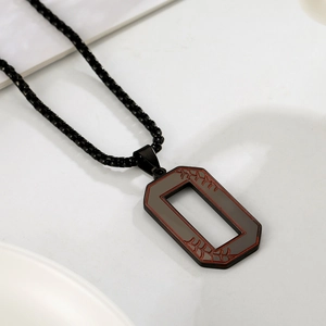 Détail du pendentif octogone gris avec texture de couture rouge sur chaîne noire