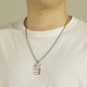 Détail macro du pendentif numéro 5 argenté avec coutures de baseball sur chaîne
