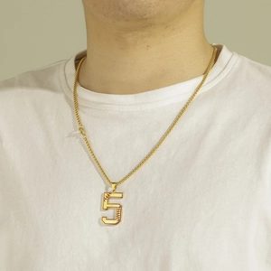 Détail du collier à chaîne box dorée avec pendentif chiffre 5 et coutures rouges de baseball