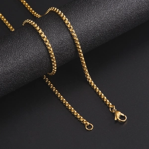Collar de cadena tipo box dorada pulida con cierre de mosquetón sobre fondo negro texturizado