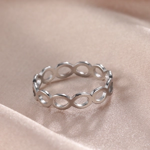 Anello infinito in acciaio inossidabile argento lucido su sfondo di seta champagne