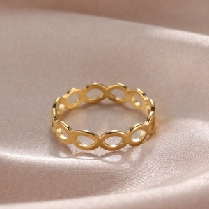 Dettaglio dell'anello dorato con simbolo infinito su sfondo lussuoso in raso champagne