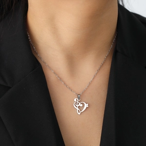 Collar de corazón y nota musical bañado en oro de 18K usado sobre un blazer negro elegante