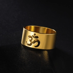 Macro shot of polished gold-finished stainless steel ring with a cutout Yoga Om symbol