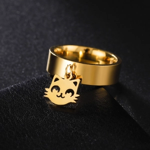 Macro shot of gold stainless steel ring with cute cat head pendant on leather background